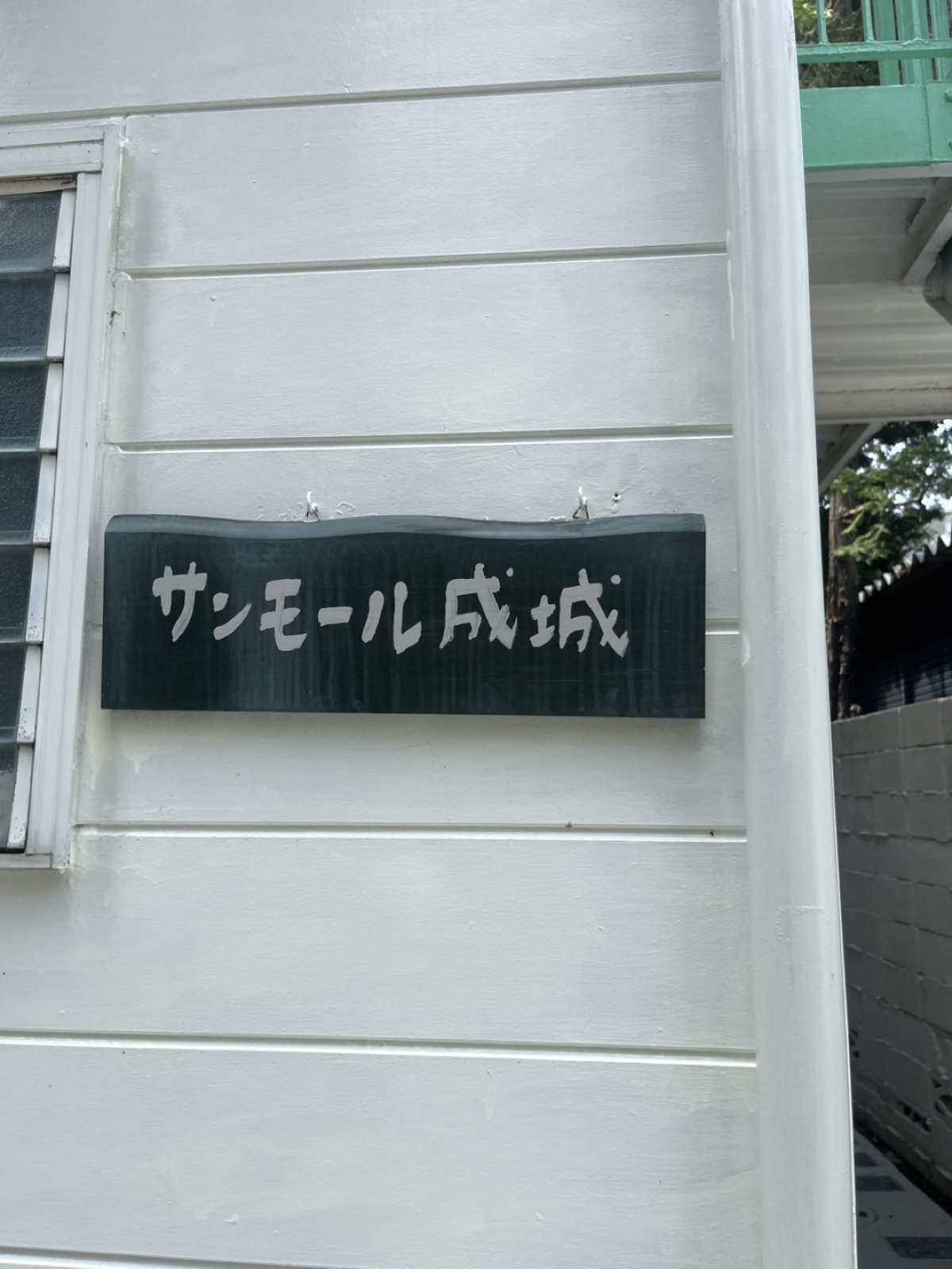 建物の壁に掛かった「サンモール成城」の木の看板
